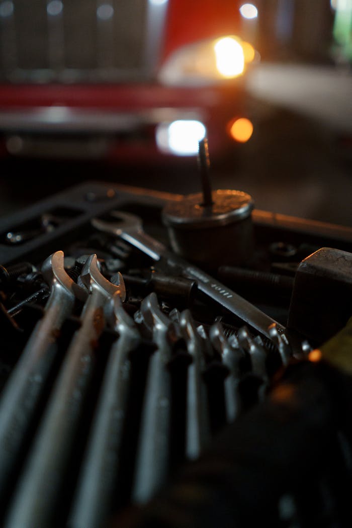 Close-up of mechanics tools with classic car in the background, lit for night work ambiance.