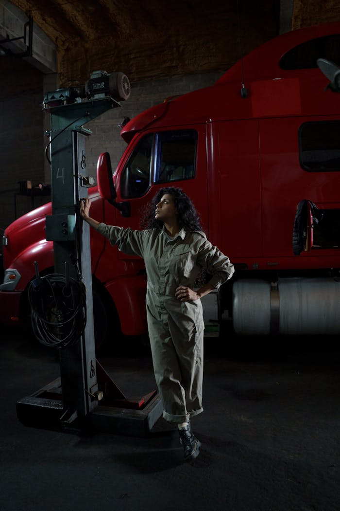 Woman mechanic inspecting equipment in a truck garage, showcasing strength and capability.