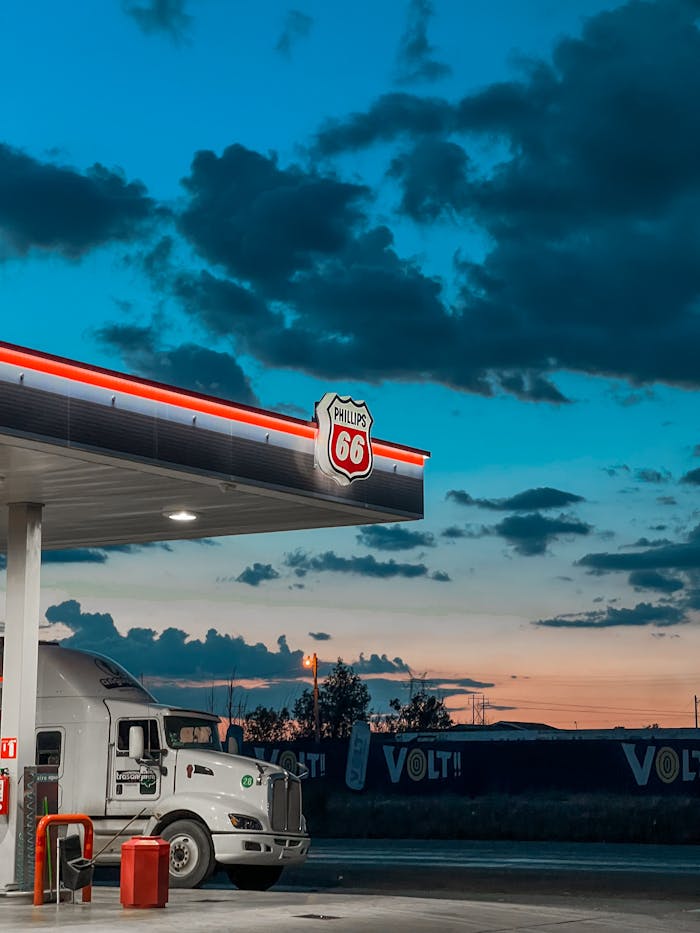 A tractor-trailer parked at a Phillips 66 gas station during a colorful twilight sky in Cuauhtémoc, Chihuahua, Mexico.